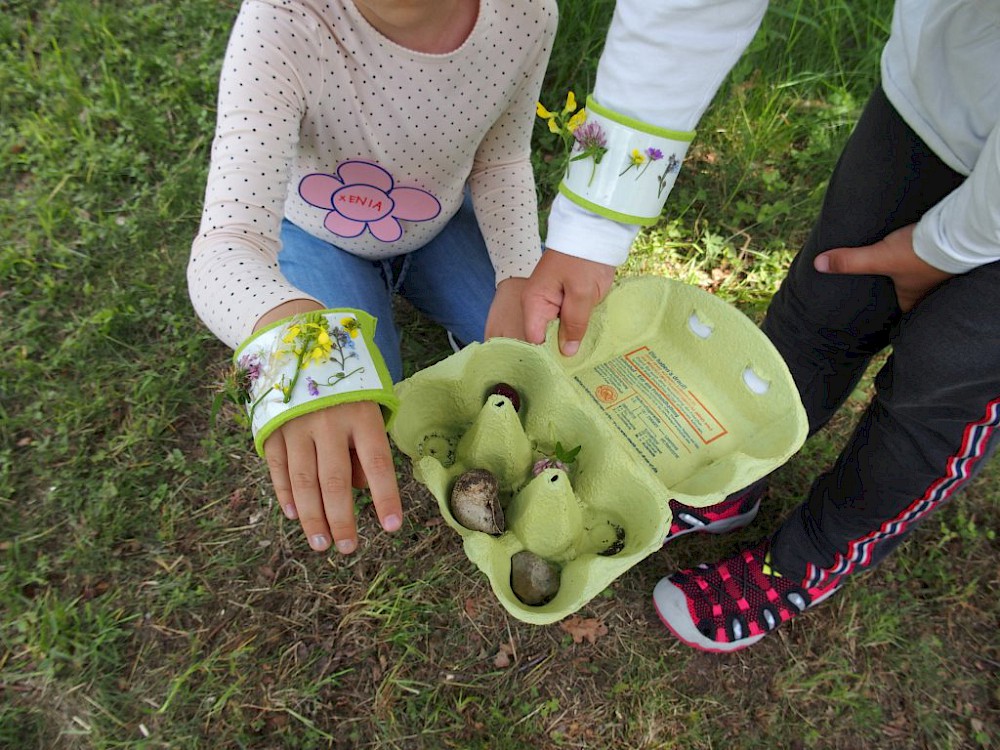 Zwei stolze ABC-Kinder zeigen ihre Teamarbeit, ihre selbst erstellten Blütenarmbänder und gefundenen Sammelstücke im Eierbecher. Foto: Bernd Rabe