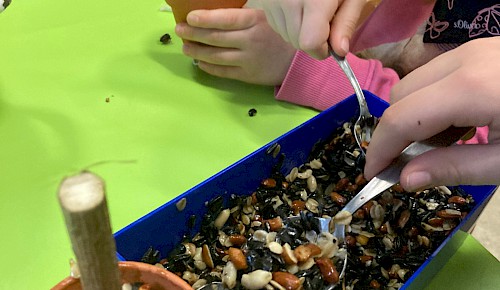 Kita Kinder befüllen Vogelfuttertöpfchen